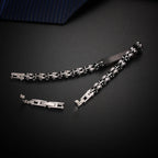 Two-tone men's bracelet with black ceramic and silver steel links on a dark surface