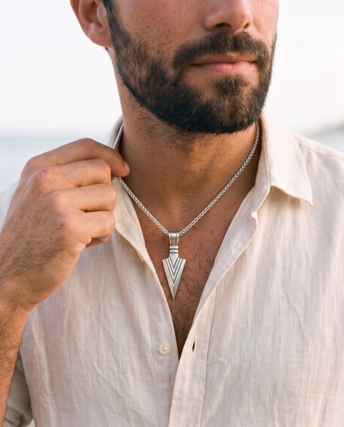 Man adjusting the Marco Maveri Arrowhead Pendant Wheat Chain Necklace, close-up, Silver
