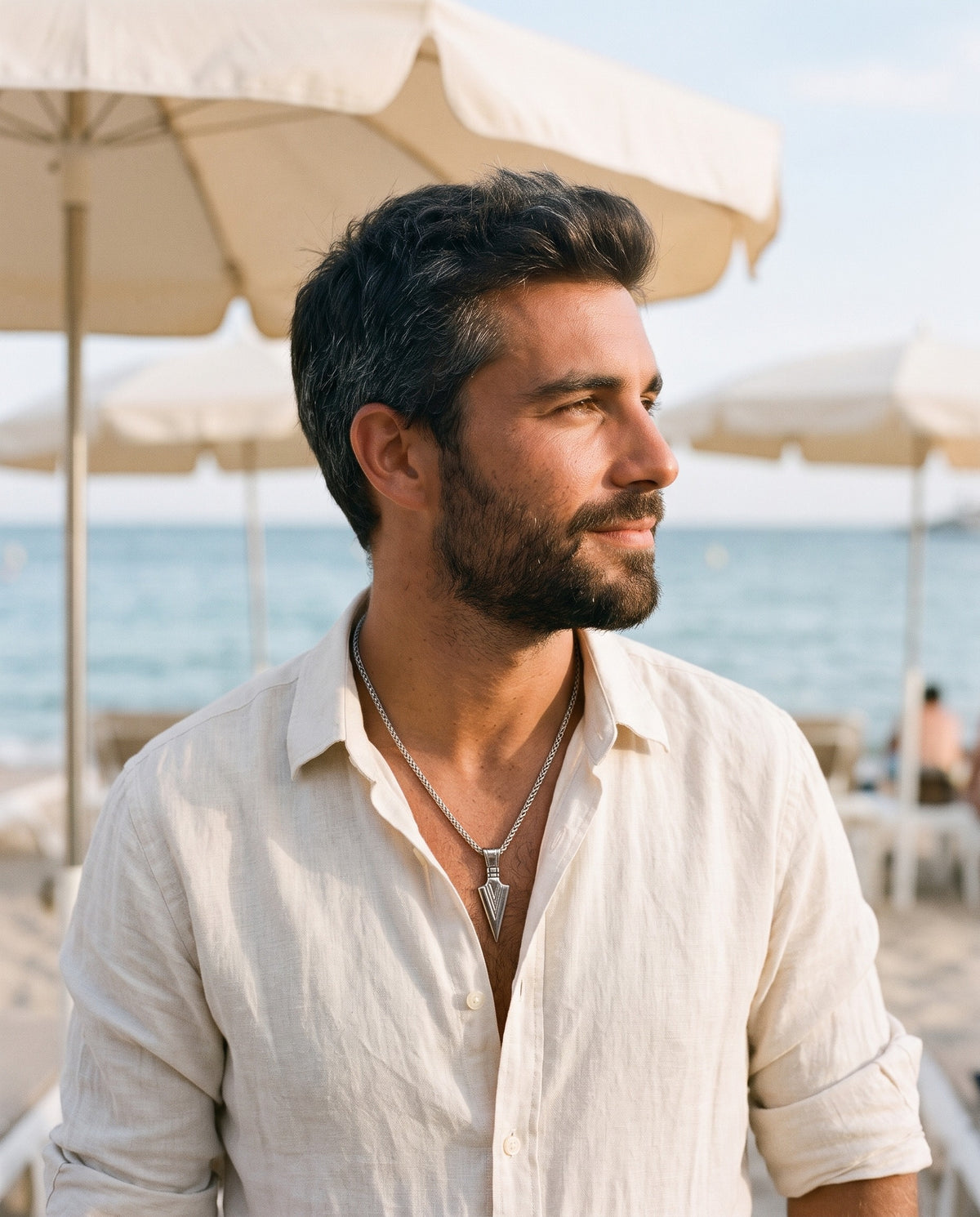 Man wearing the Marco Maveri Arrowhead Pendant Wheat Chain Necklace by the sea, Silver