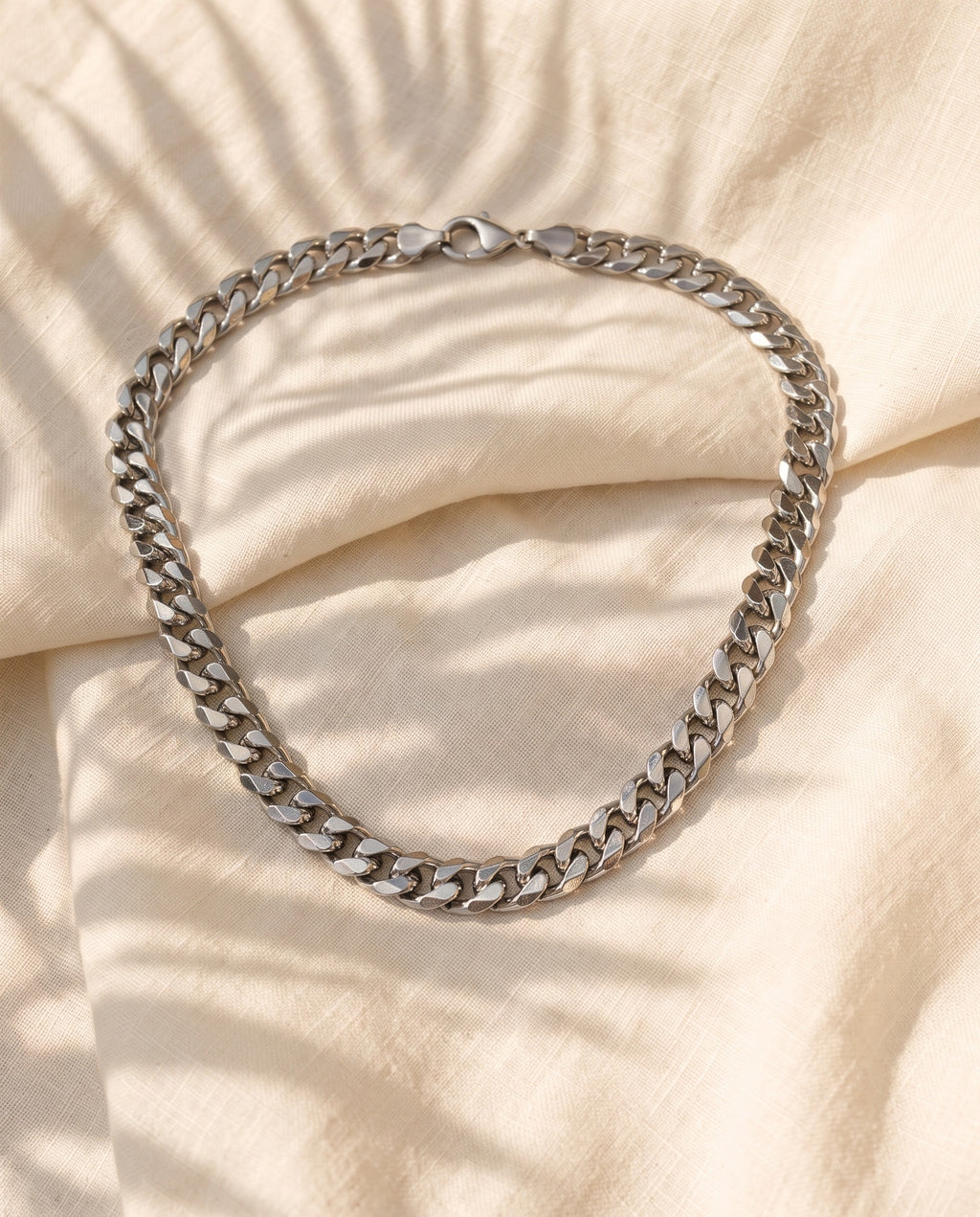 Marco Maveri Bold Cuban Link Chain in Titanium Steel laid on cream linen, Silver