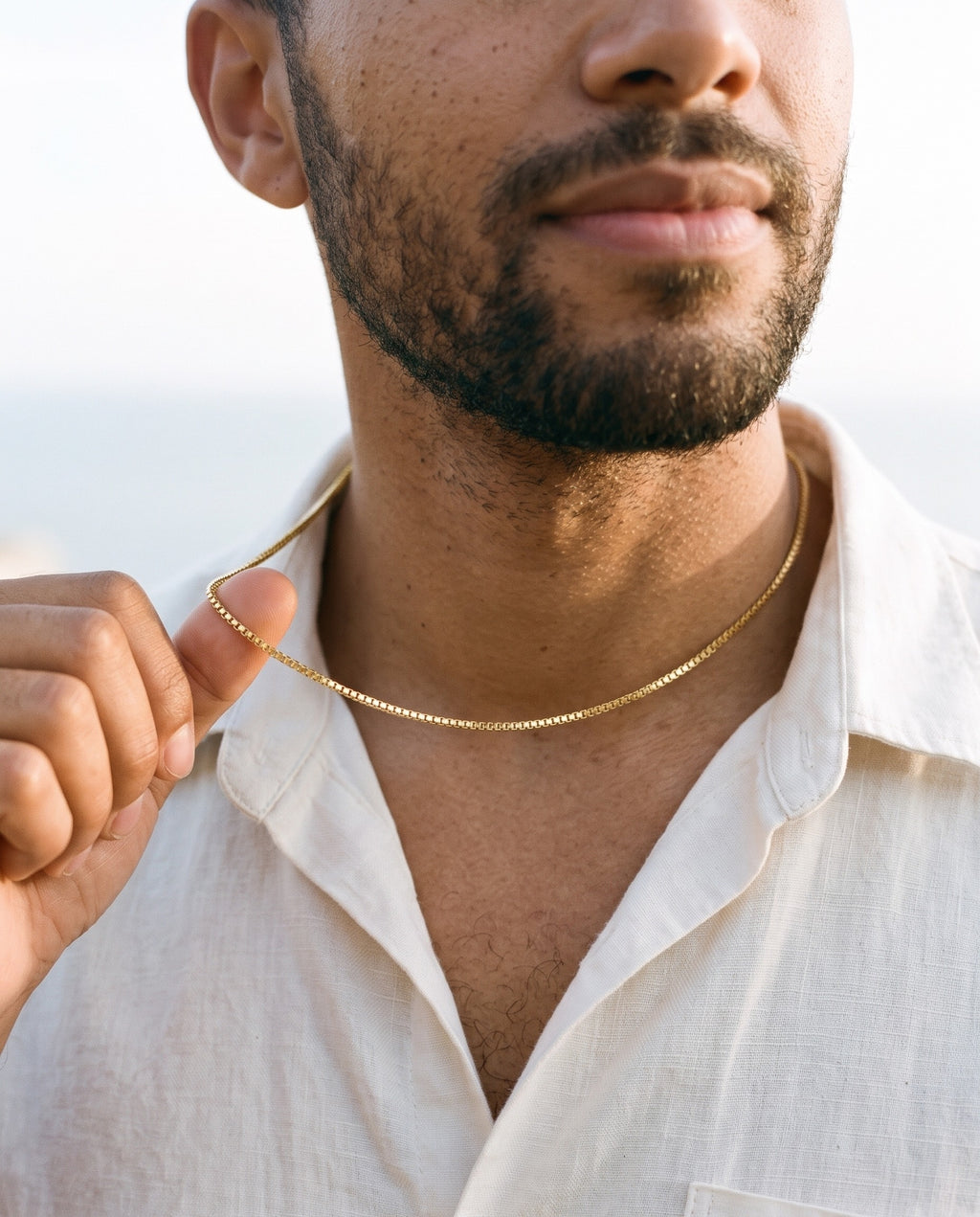 Man adjusting the Marco Maveri Box Chain Necklace in Titanium Steel, close-up, Gold