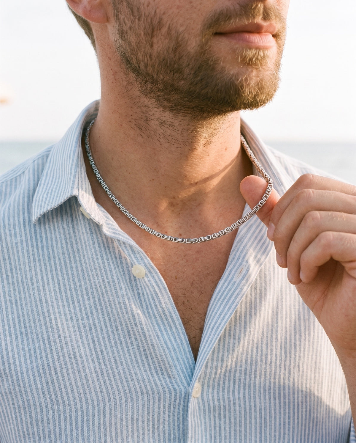 Man adjusting the Marco Maveri Byzantine Chain in Stainless Steel, close-up, Silver