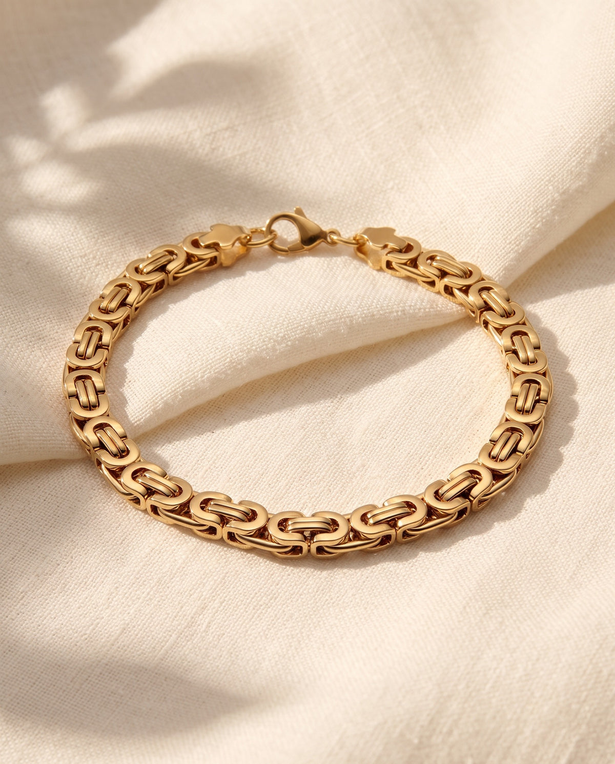 Marco Maveri Byzantine Link Chain Bracelet laid on cream linen, Gold