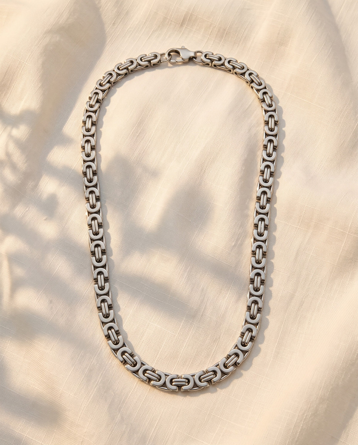 Marco Maveri Byzantine Link Chain Necklace laid on cream linen, Silver