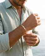 Man adjusting the Marco Maveri Cable Bracelet with Bar Detail, close-up, Gold