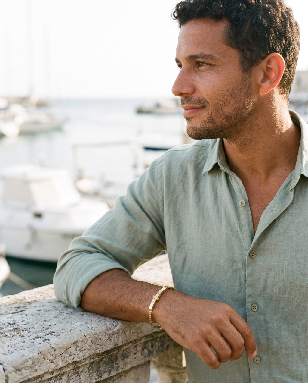 Man wearing the Marco Maveri Cable Bracelet with Bar Detail by the sea, Gold