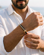 Man adjusting the Marco Maveri Cable Cuff Bracelet, close-up, Black / Gold