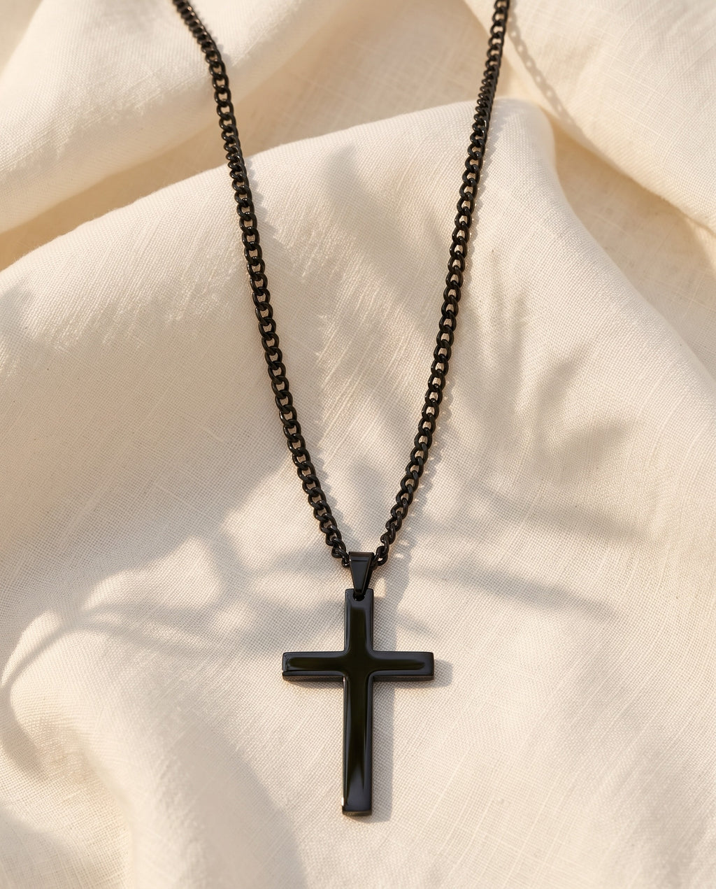 Marco Maveri Classic Cross Pendant Necklace laid on cream linen, Black