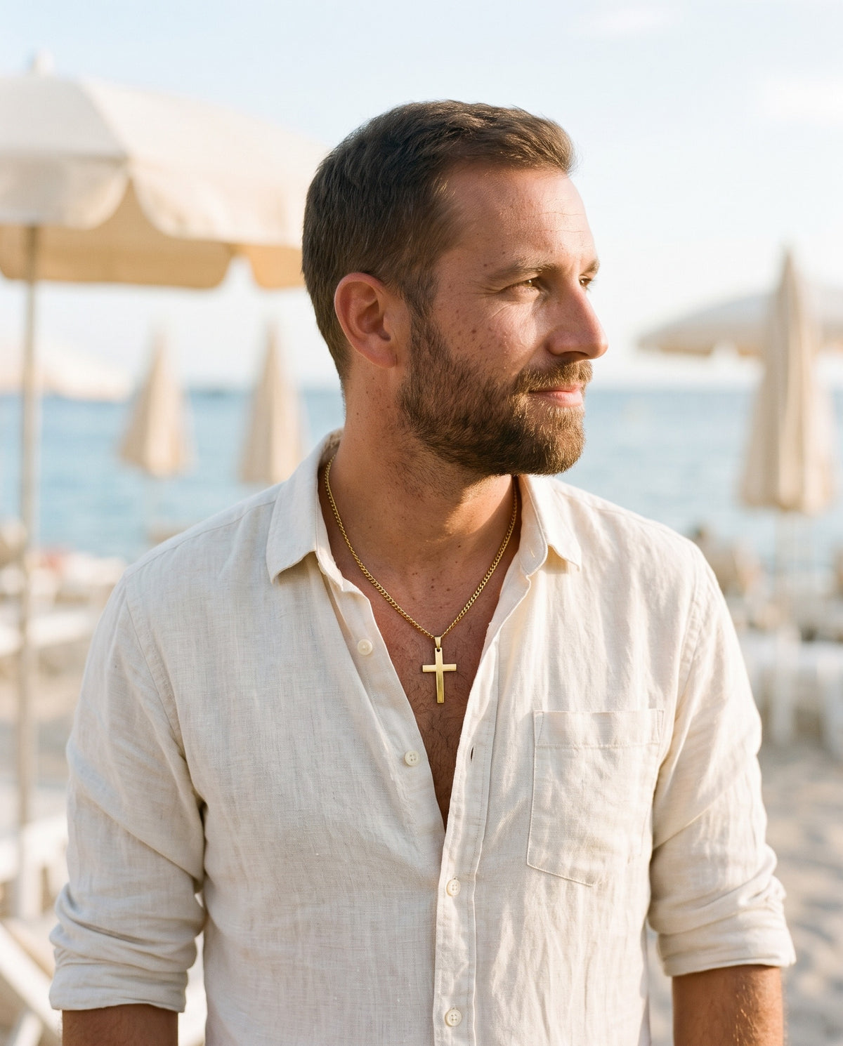 Man wearing the Marco Maveri Classic Cross Pendant Necklace by the sea, Gold