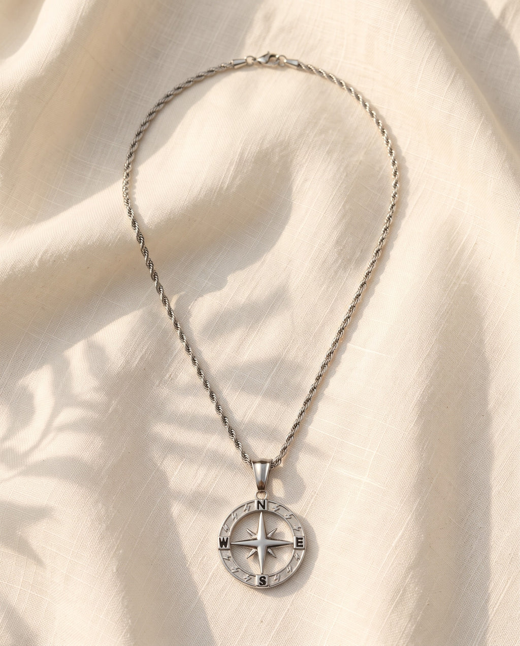Marco Maveri Compass Pendant Rope Chain Necklace laid on cream linen, Silver