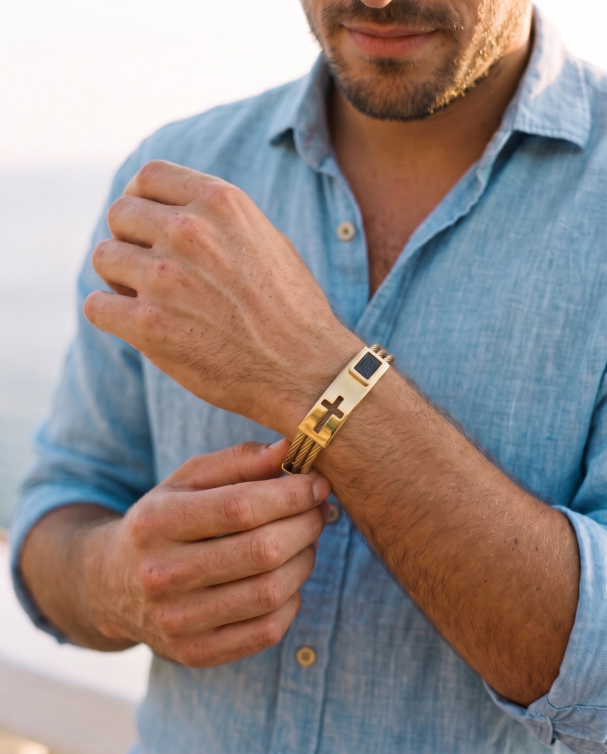 Man adjusting the Marco Maveri Cross Inlay Titanium Steel Bracelet, close-up, Gold