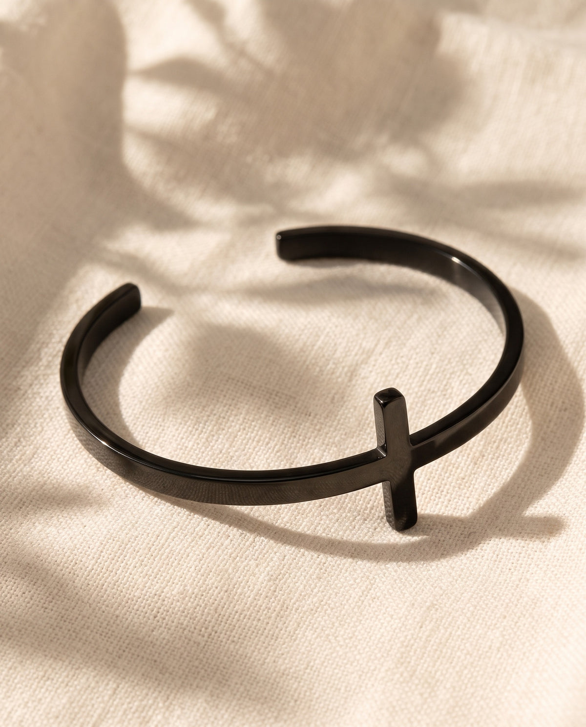 Marco Maveri Cross Motif Cuff Bracelet laid on cream linen, Black