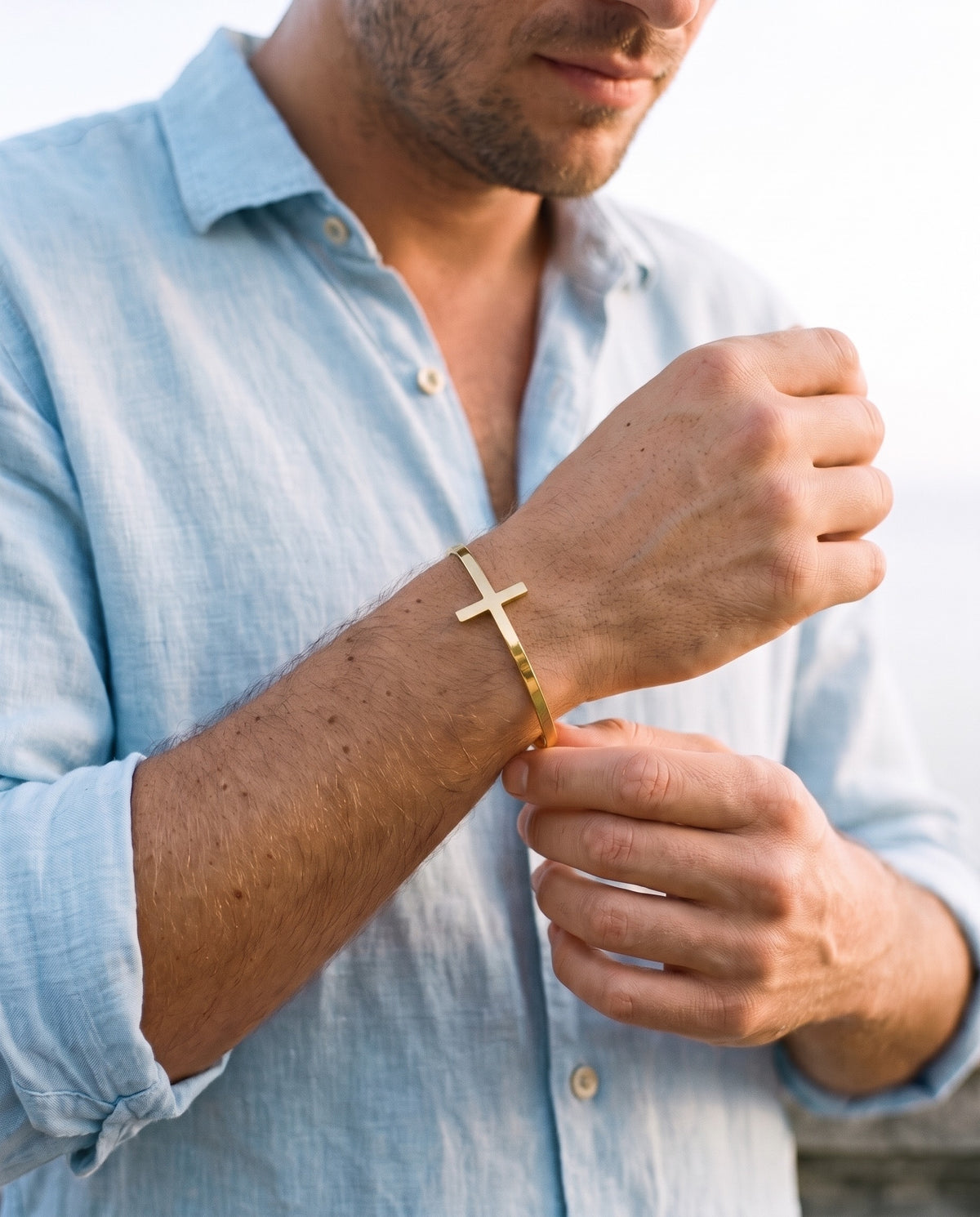 Man adjusting the Marco Maveri Cross Motif Cuff Bracelet, close-up, Gold