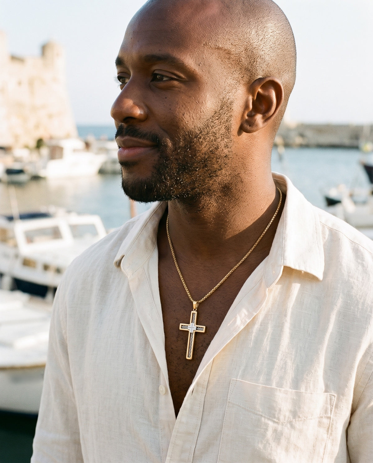 Man wearing the Marco Maveri Cross Pendant Necklace with Cable Inlay by the sea, Gold
