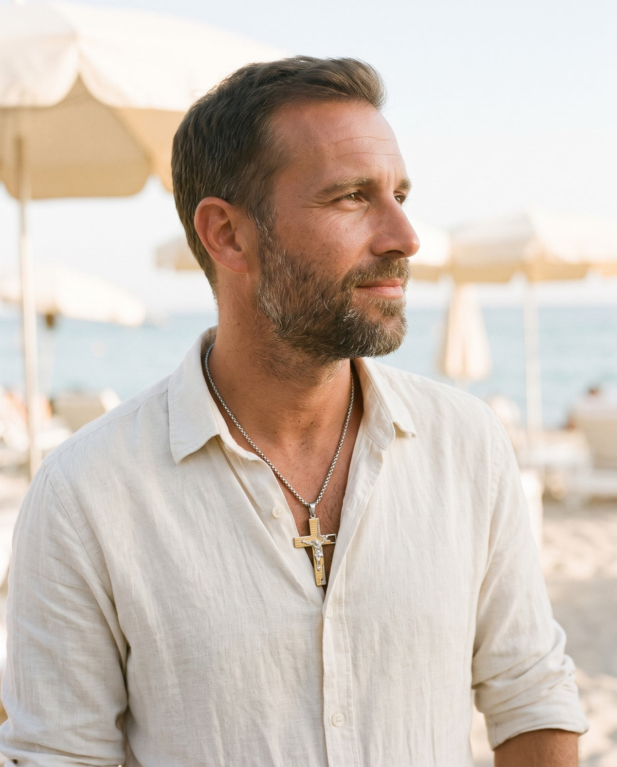 Man wearing the Marco Maveri Crucifix Pendant Necklace in Titanium Steel by the sea, Gold