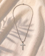 Marco Maveri Crucifix Pendant Necklace in Titanium Steel laid on cream linen, Silver