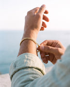 Man adjusting the Marco Maveri Cuban Link Bracelet in Stainless Steel, close-up, Gold