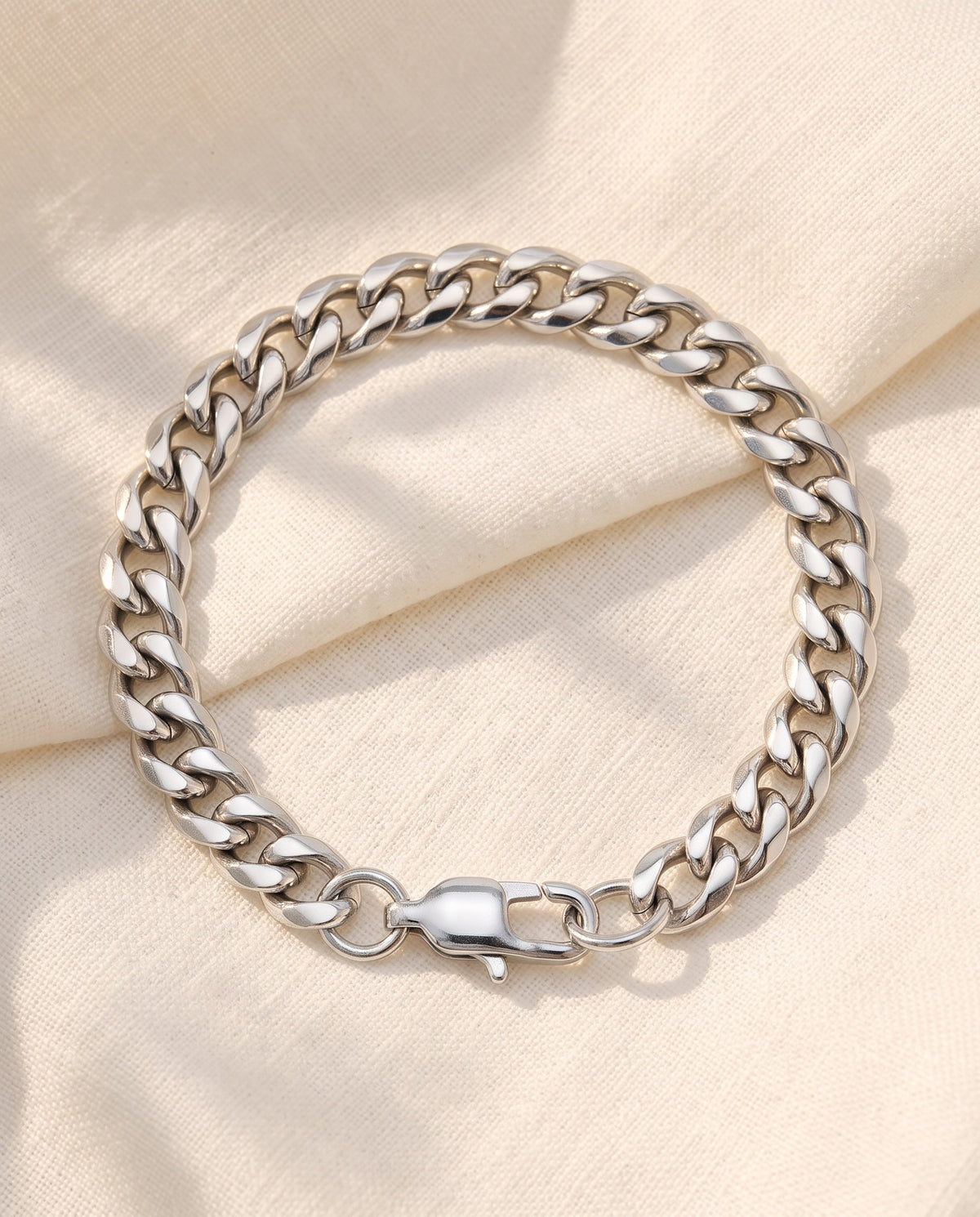 Marco Maveri Cuban Link Bracelet in Stainless Steel laid on cream linen, Silver