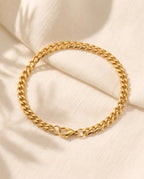 Marco Maveri Cuban Link Chain Bracelet laid on cream linen, Gold