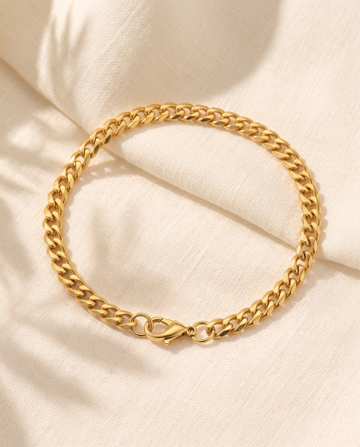 Marco Maveri Cuban Link Chain Bracelet laid on cream linen, Gold
