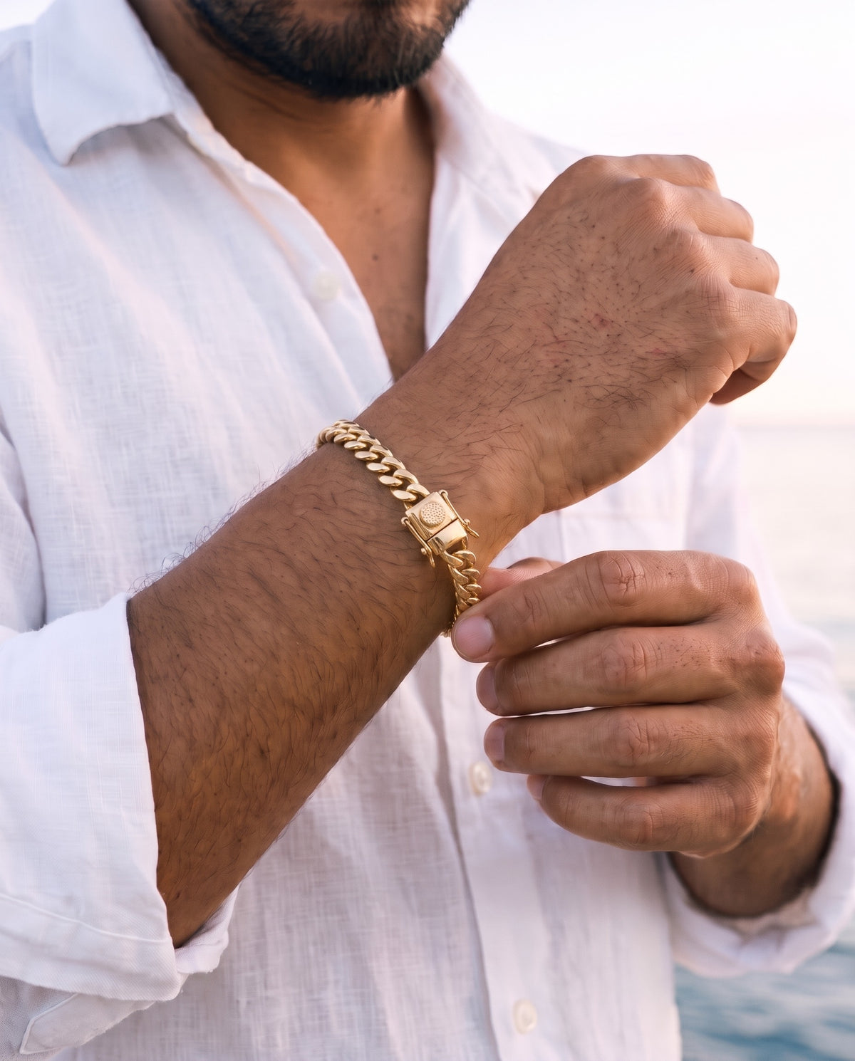 Man adjusting the Marco Maveri Cuban Link Chain Bracelet with Box Clasp, close-up, Gold