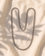 Marco Maveri Cuban Link Chain Necklace laid on cream linen, Silver