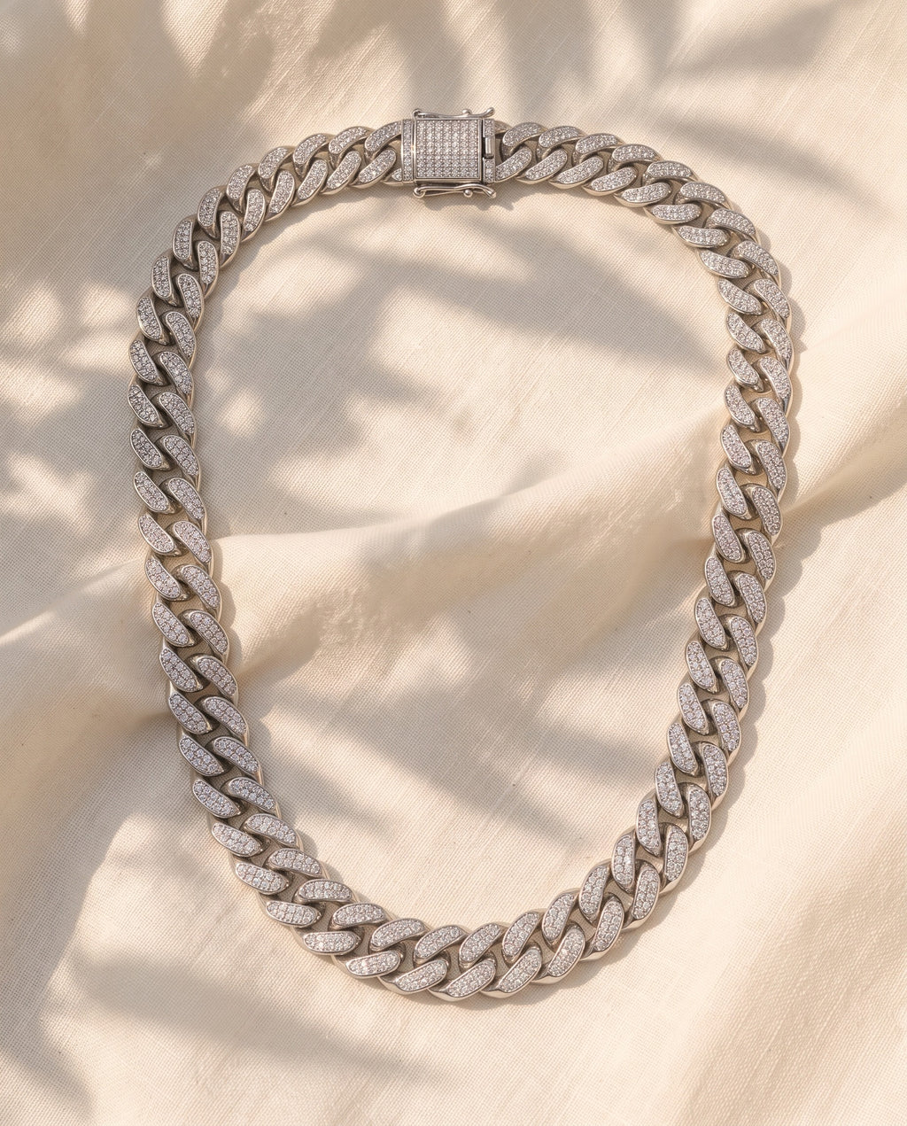 Marco Maveri Cuban Link Chain with Cubic Zirconia laid on cream linen, Silver
