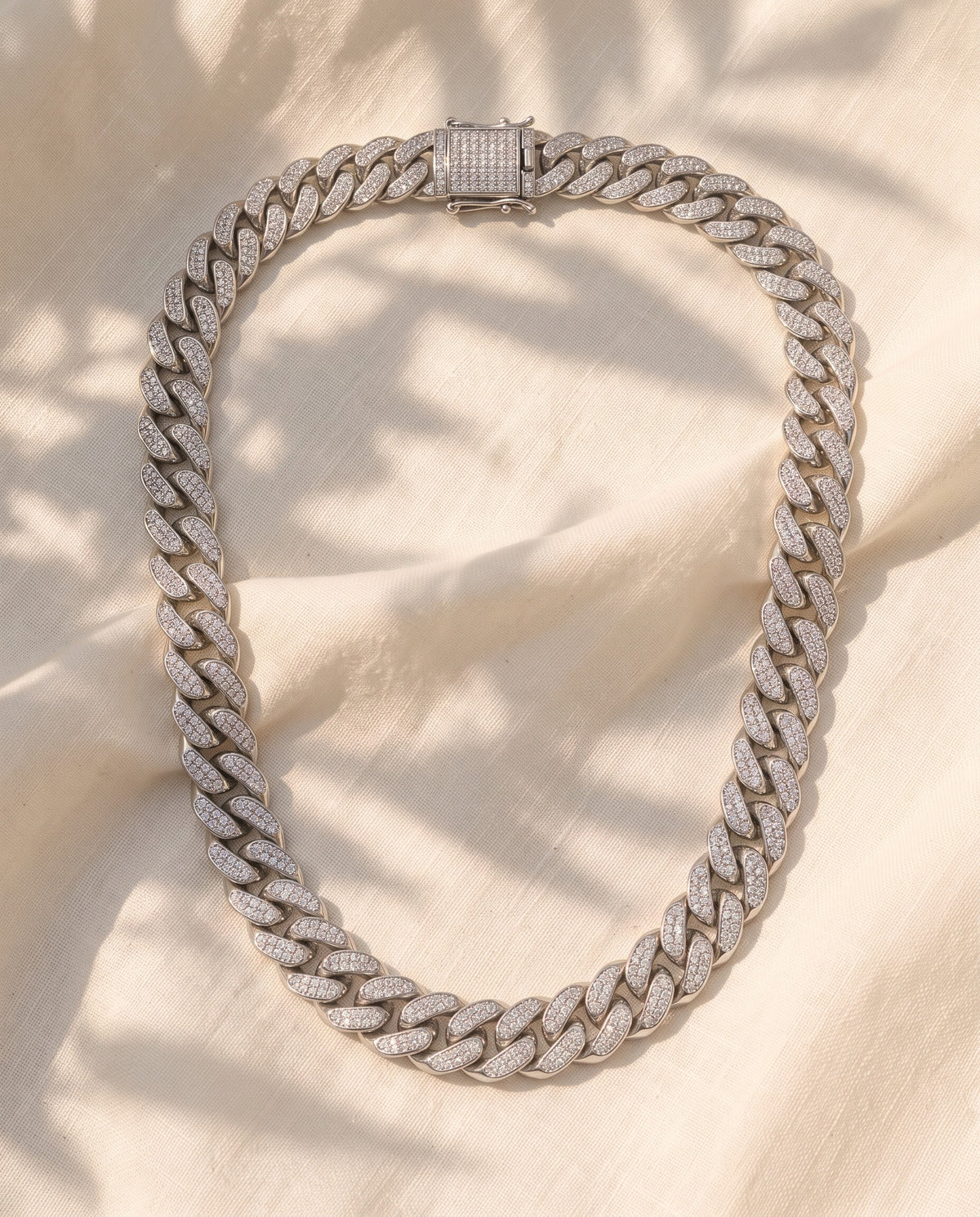 Marco Maveri Cuban Link Chain with Cubic Zirconia laid on cream linen, Silver