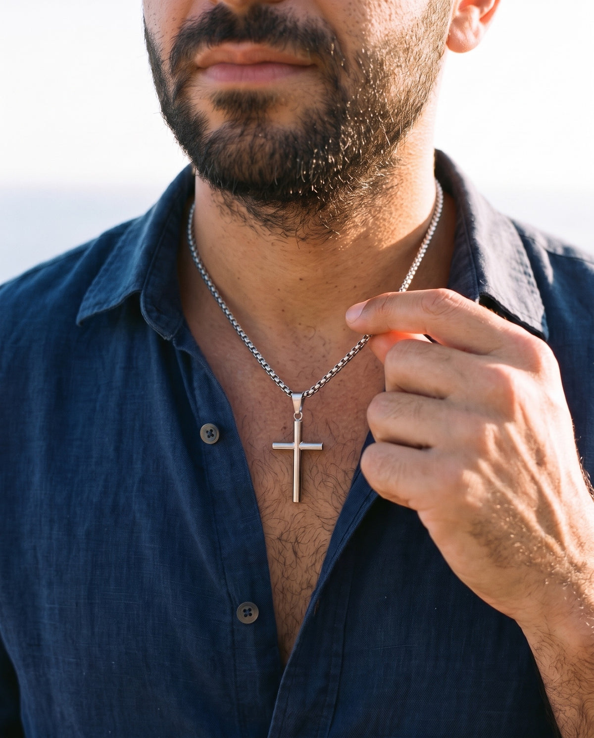 Man adjusting the Marco Maveri Cylindrical Cross Pendant Necklace, close-up, Silver
