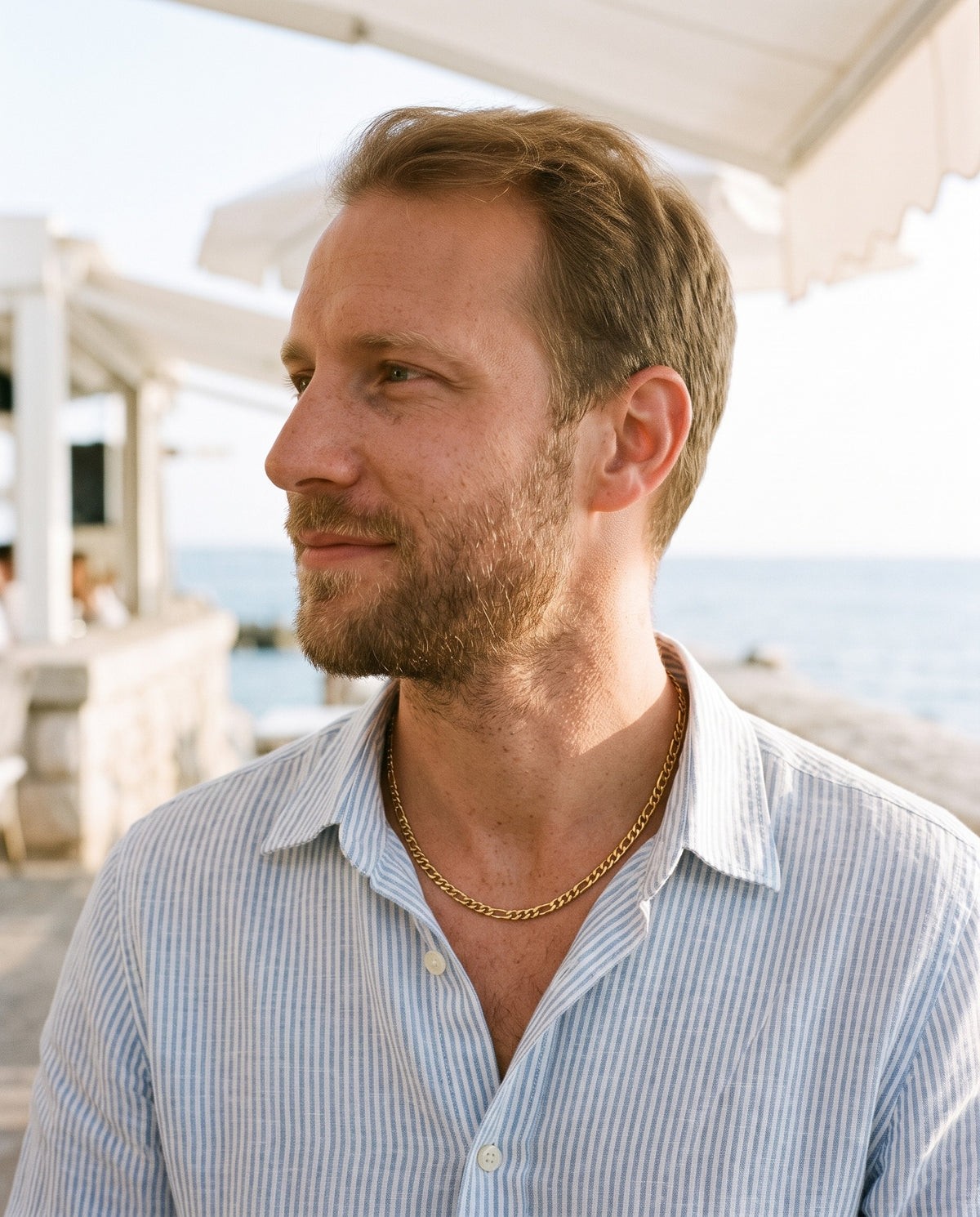 Man wearing the Marco Maveri Figaro Chain in Stainless Steel by the sea, Gold