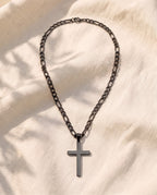 Marco Maveri Figaro Chain with Cross Pendant laid on cream linen, Black