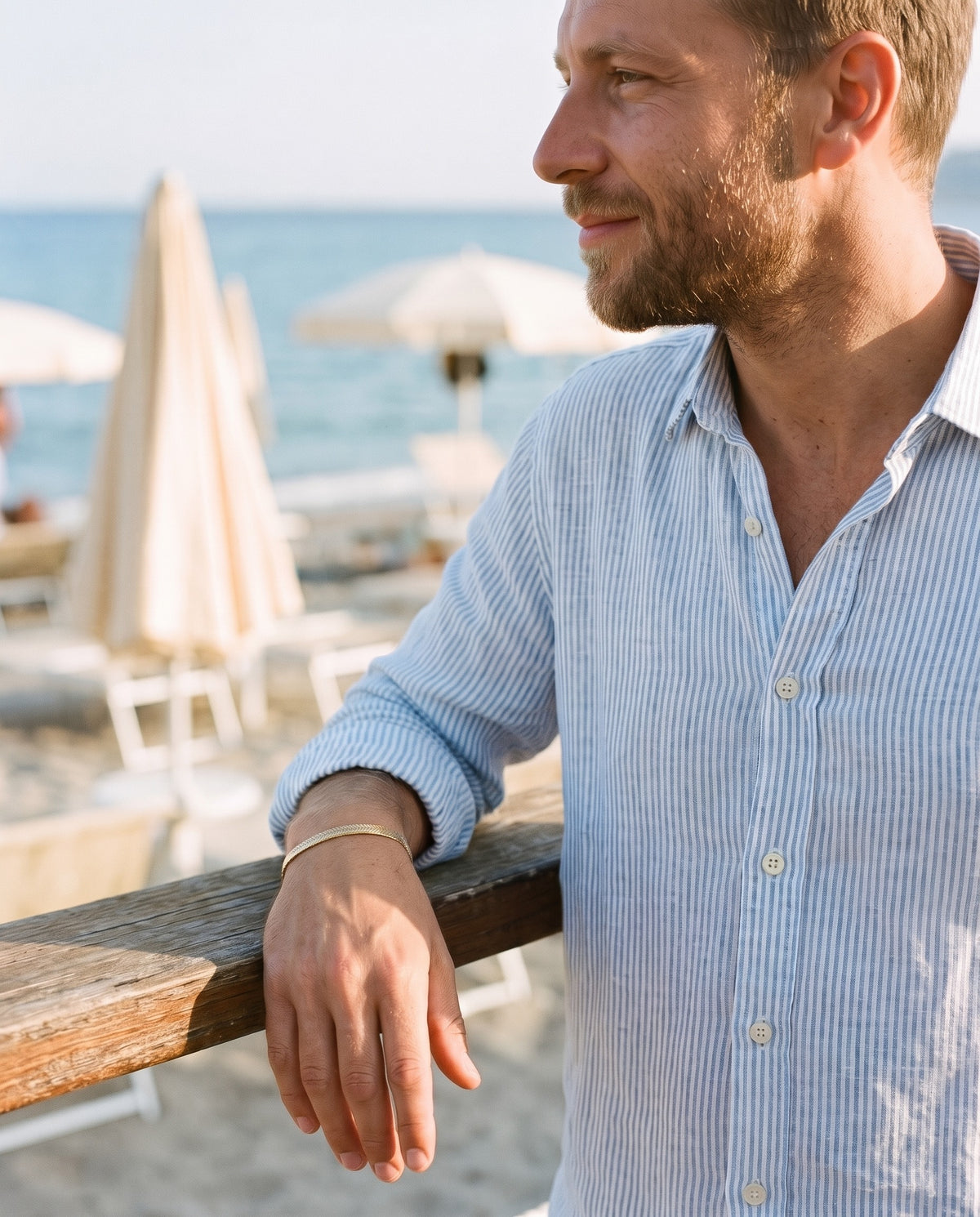 Man wearing the Marco Maveri Flat Snake Chain Bracelet by the sea, Gold