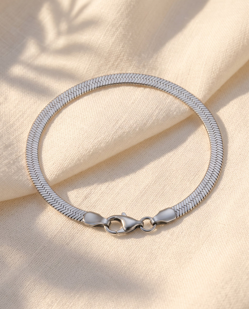 Marco Maveri Flat Snake Chain Bracelet laid on cream linen, Silver