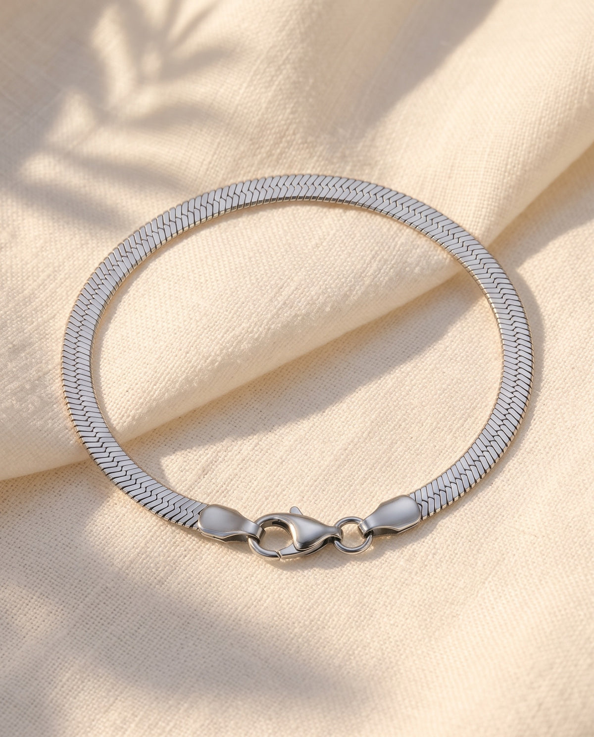 Marco Maveri Flat Snake Chain Bracelet laid on cream linen, Silver