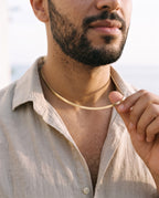 Man adjusting the Marco Maveri Flat Snake Chain Necklace, close-up, Gold