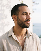 Man wearing the Marco Maveri Flat Snake Chain Necklace by the sea, Gold