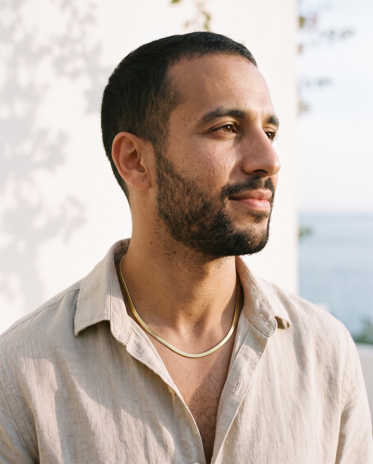 Man wearing the Marco Maveri Flat Snake Chain Necklace by the sea, Gold
