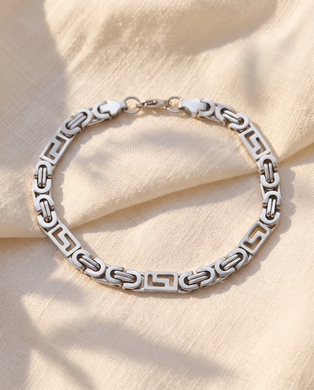 Marco Maveri Geometric Link Byzantine Bracelet laid on cream linen, Silver
