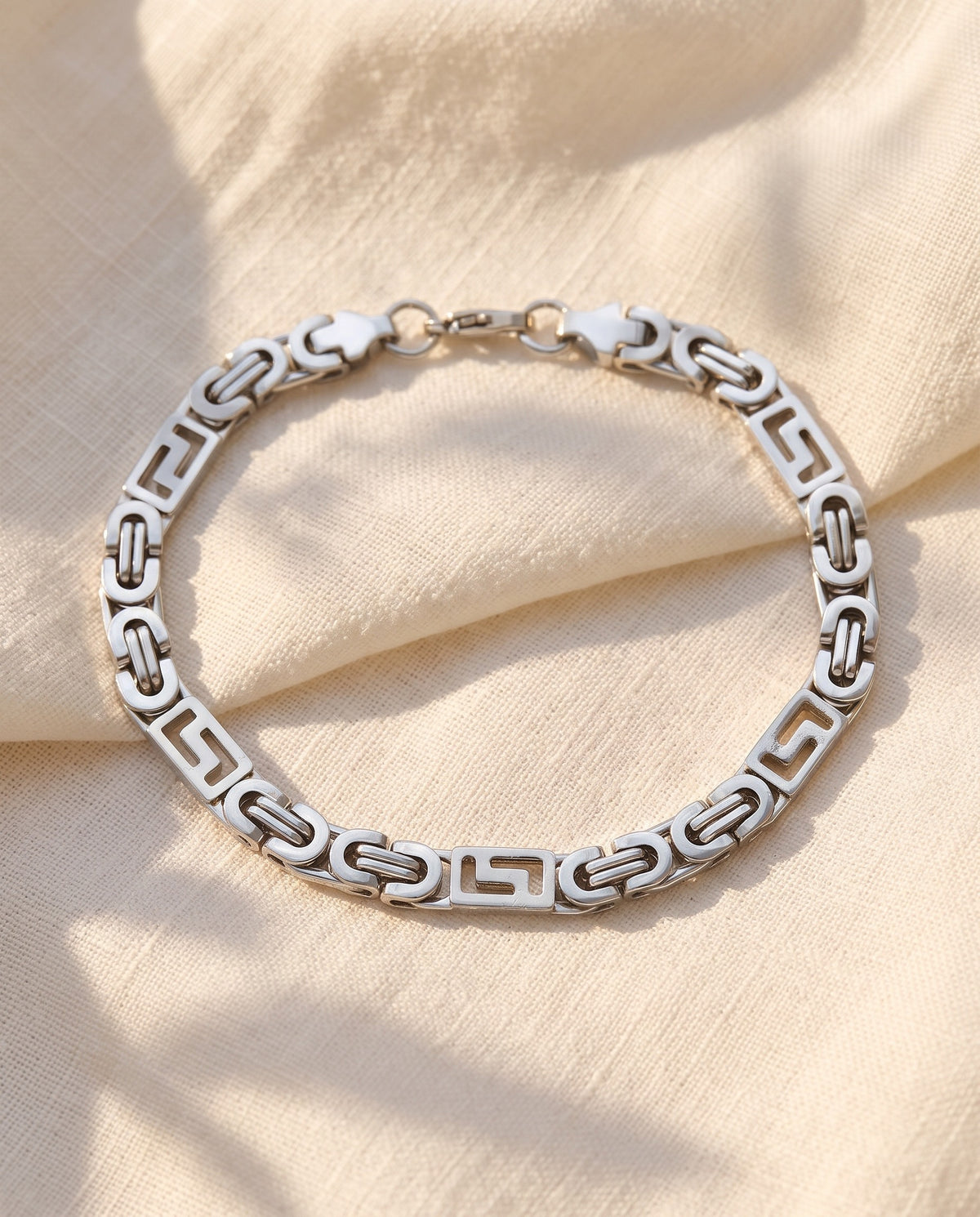 Marco Maveri Geometric Link Byzantine Bracelet laid on cream linen, Silver