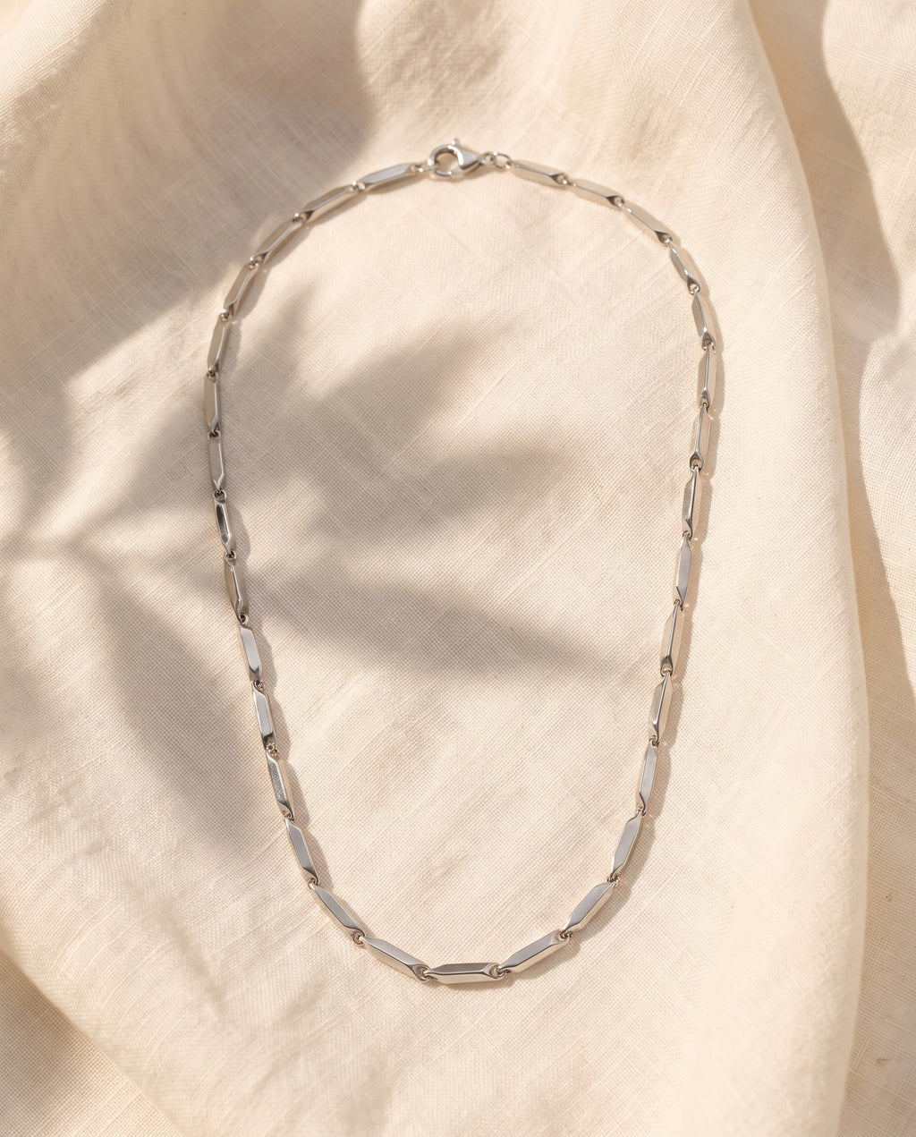 Marco Maveri Geometric Link Chain in Stainless Steel laid on cream linen, Silver
