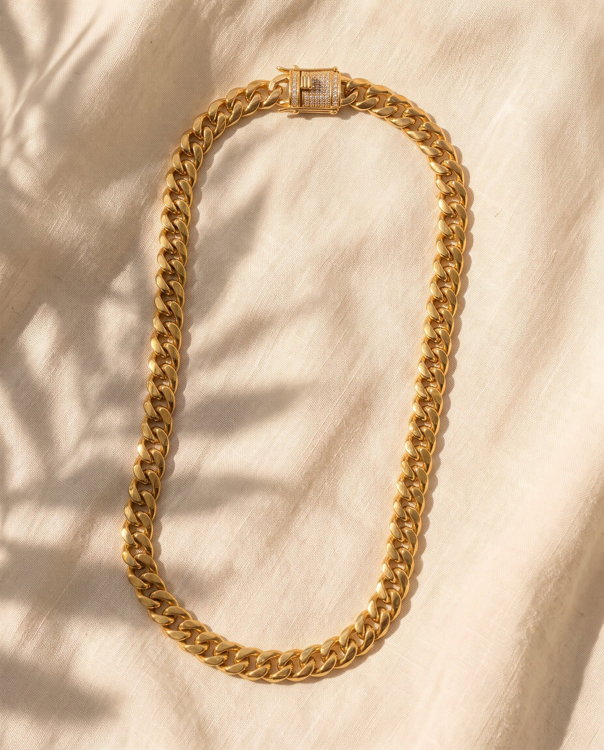 Marco Maveri Gold-Tone Cuban Link Chain laid on cream linen, Gold