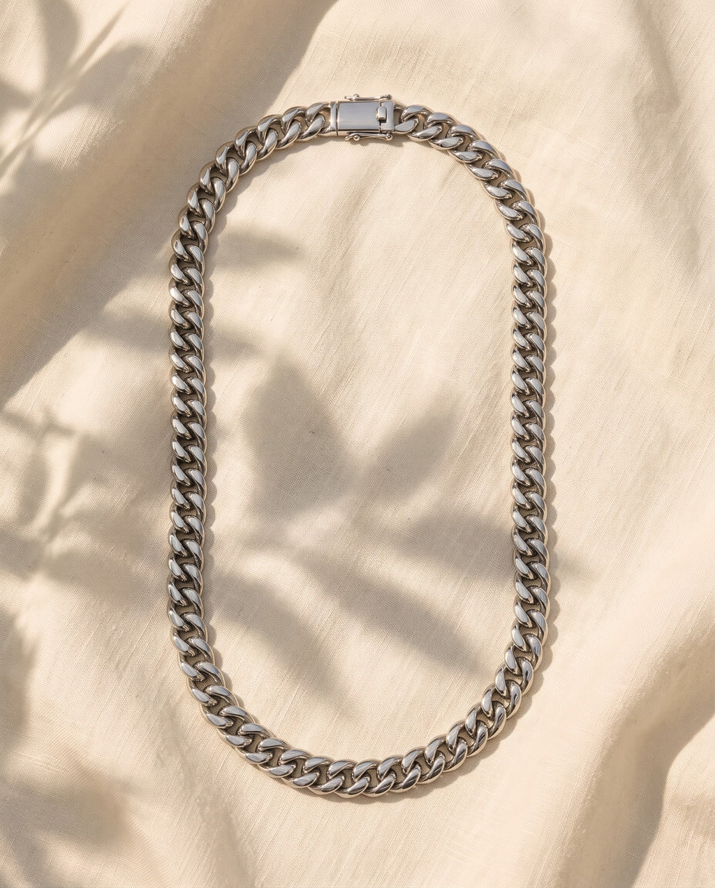 Marco Maveri Heavy Curb Chain Necklace laid on cream linen, Silver