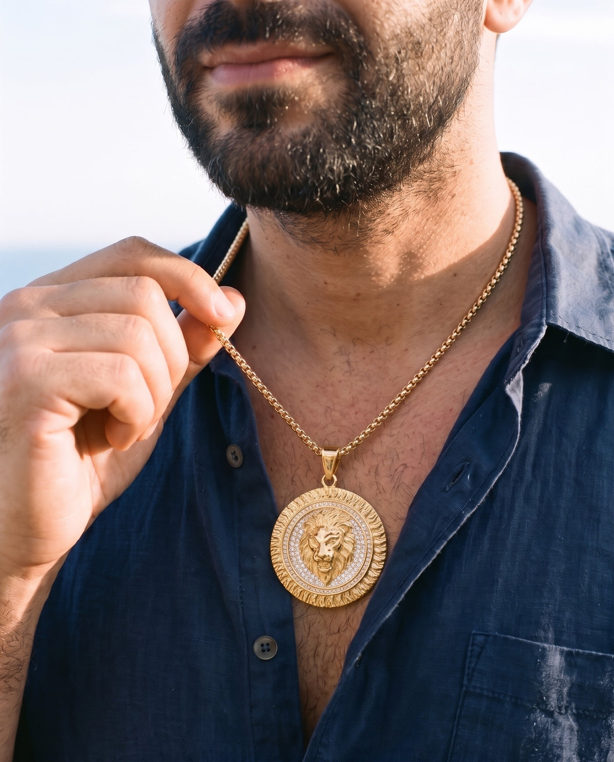 Man adjusting the Marco Maveri Lion Head Medallion Pendant Necklace, close-up, Gold