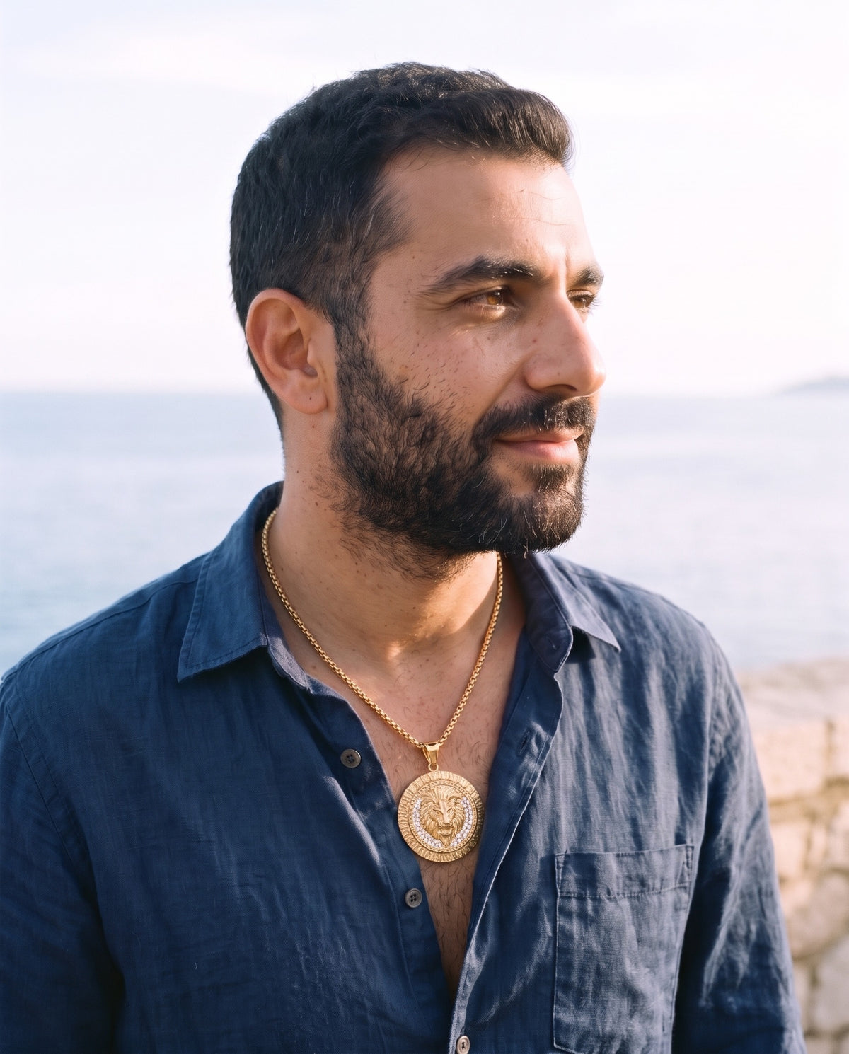 Man wearing the Marco Maveri Lion Head Medallion Pendant Necklace by the sea, Gold