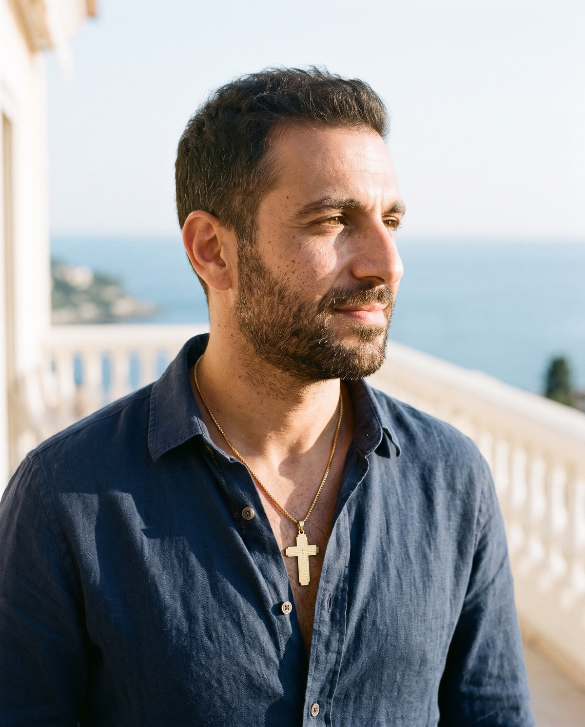 Man wearing the Marco Maveri Lord's Prayer Cross Pendant Necklace by the sea, Gold