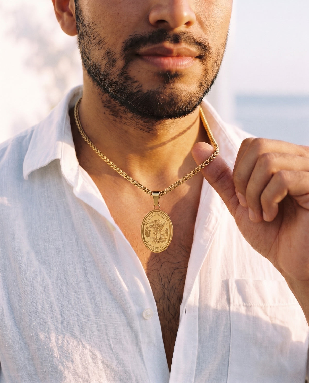Man adjusting the Marco Maveri Oval Medallion Pendant Necklace, close-up, Gold