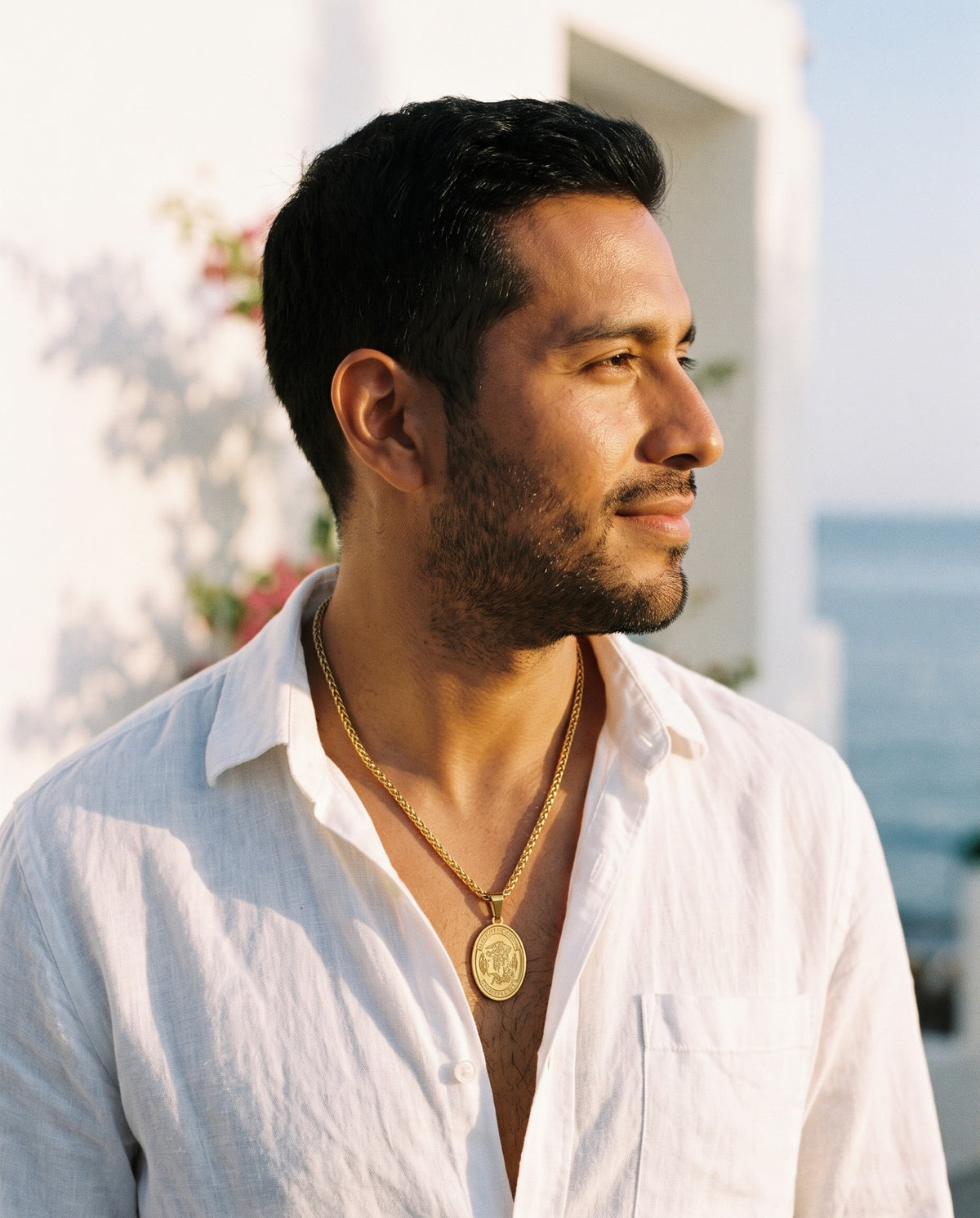 Man wearing the Marco Maveri Oval Medallion Pendant Necklace by the sea, Gold