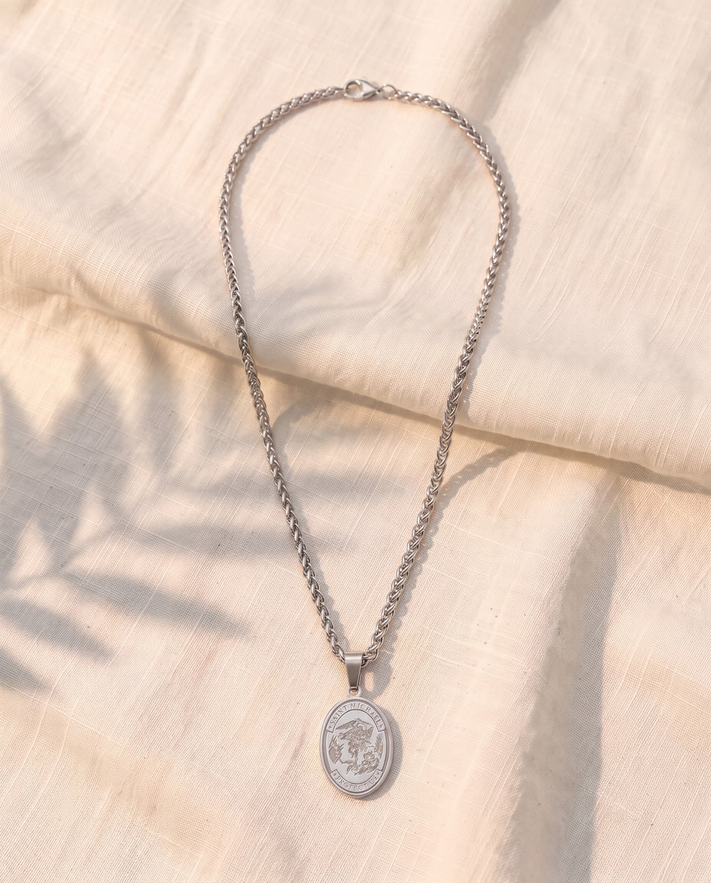 Marco Maveri Oval Medallion Pendant Necklace laid on cream linen, Silver