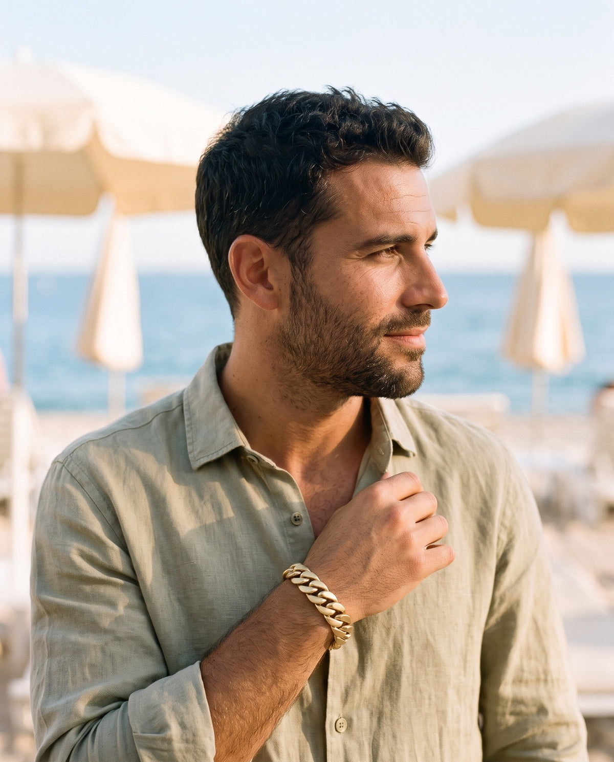 Man wearing the Marco Maveri Polished Curb Link Bracelet by the sea, Gold