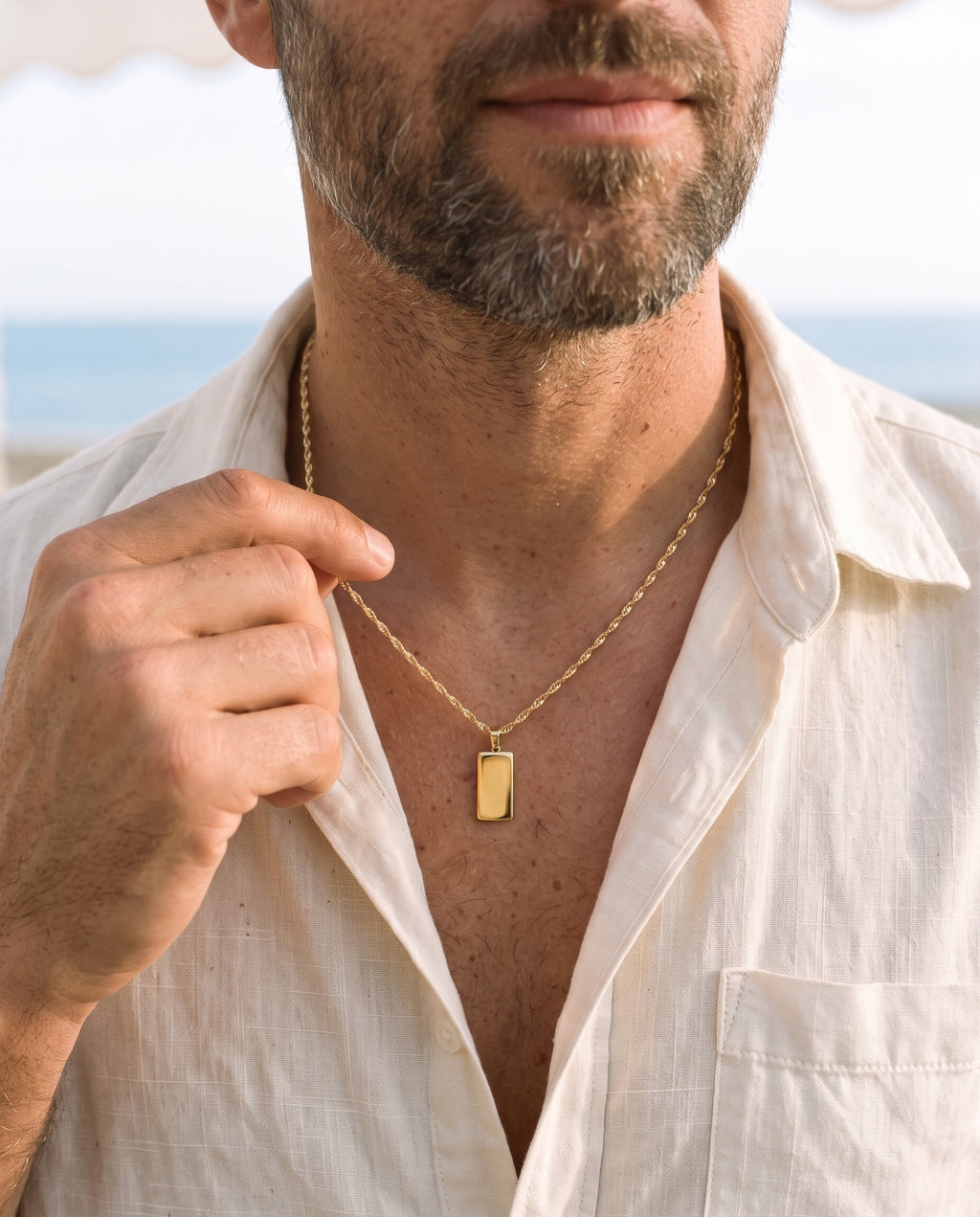 Man adjusting the Marco Maveri Rectangular Bar Pendant Necklace, close-up, Gold